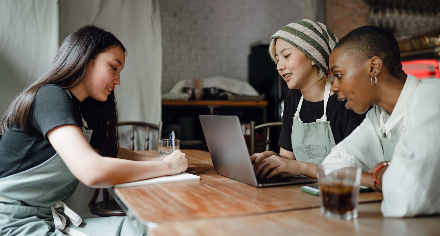 Learners working through a project together over a laptop and notes
