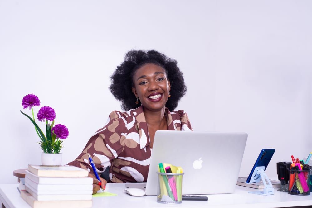 An accountant smiling at her desk with her laptop and reference books